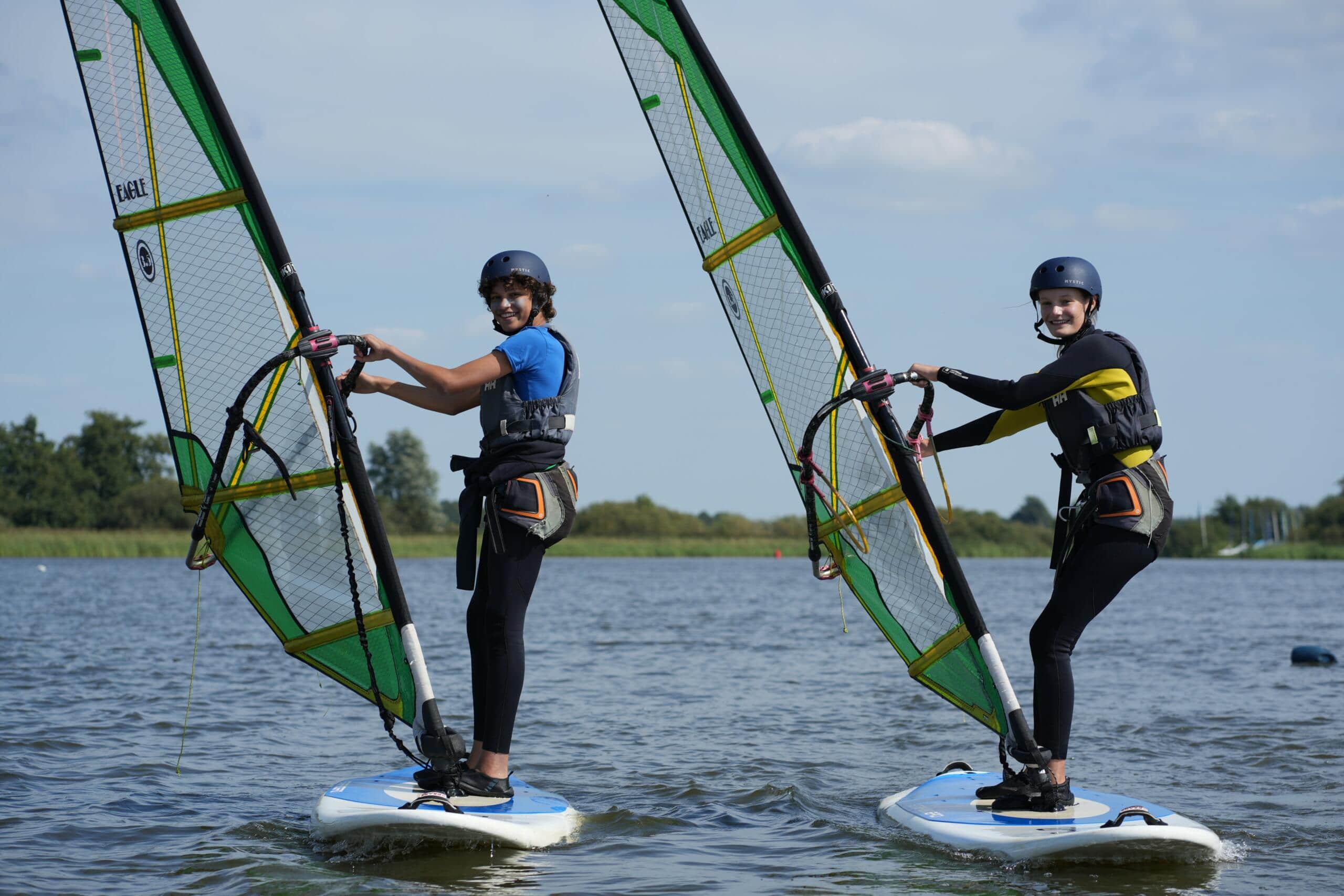Twee jonge mensen aan het windsurfen
